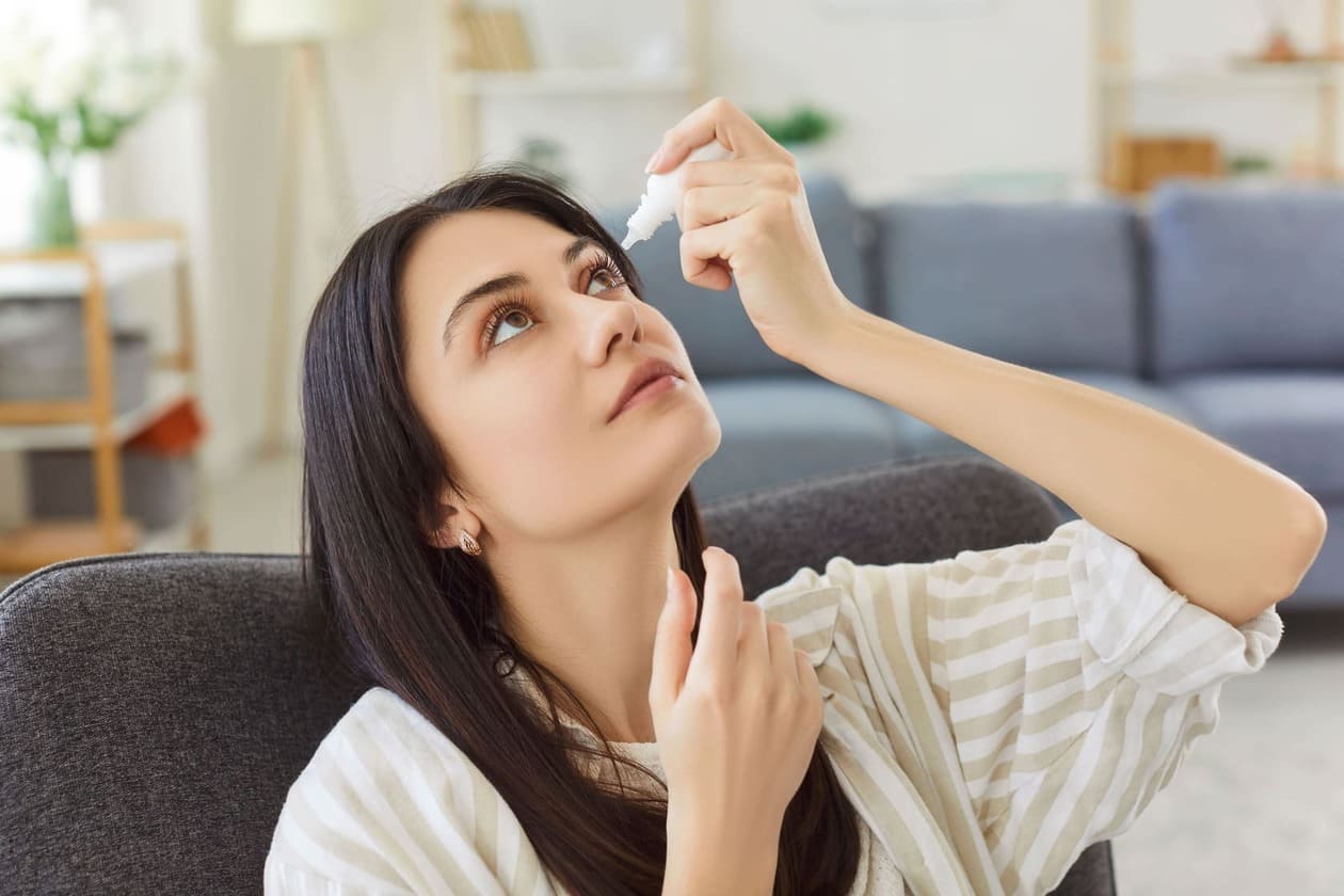 Mujer poniéndose gotas para los ojos para tratar una afección de conjuntivitis