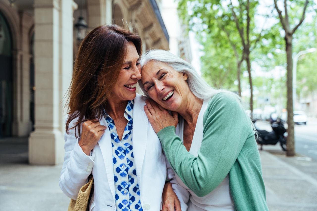 Dos mujeres sonriendo mientras comparten un grato momento.