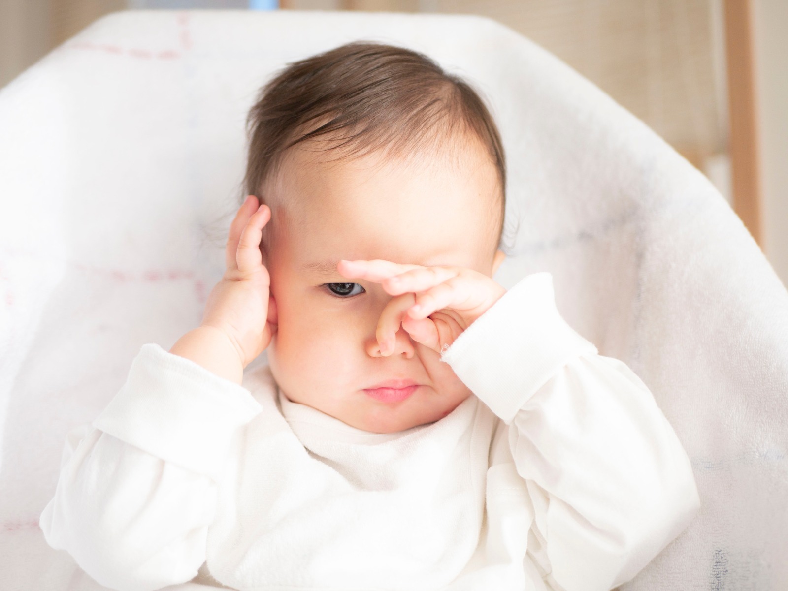 Bebé frotándose los ojos, posible signo de irritación ocular o molestia visual.