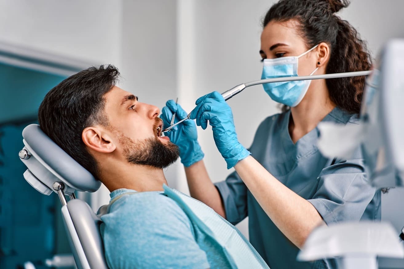 Dentista examina a un paciente en la consulta, realizando limpieza profesional para tratar la gingivitis y prevenir enfermedades bucales. 